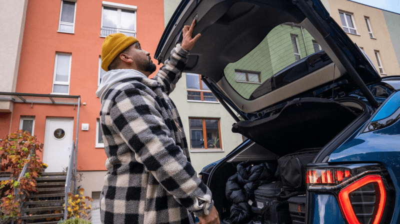 Man in yellow hat closing a trunk.