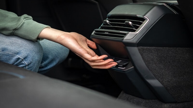 A hand operating the controls beneath the central air vent in a Lynk & Co car.