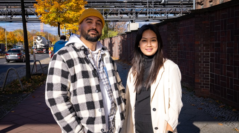 An image of a man and a woman standing on a city street facing the camera.